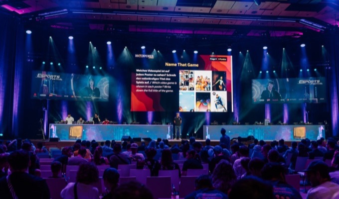 Quiz show in front of a full hall — hundreds play along at once
